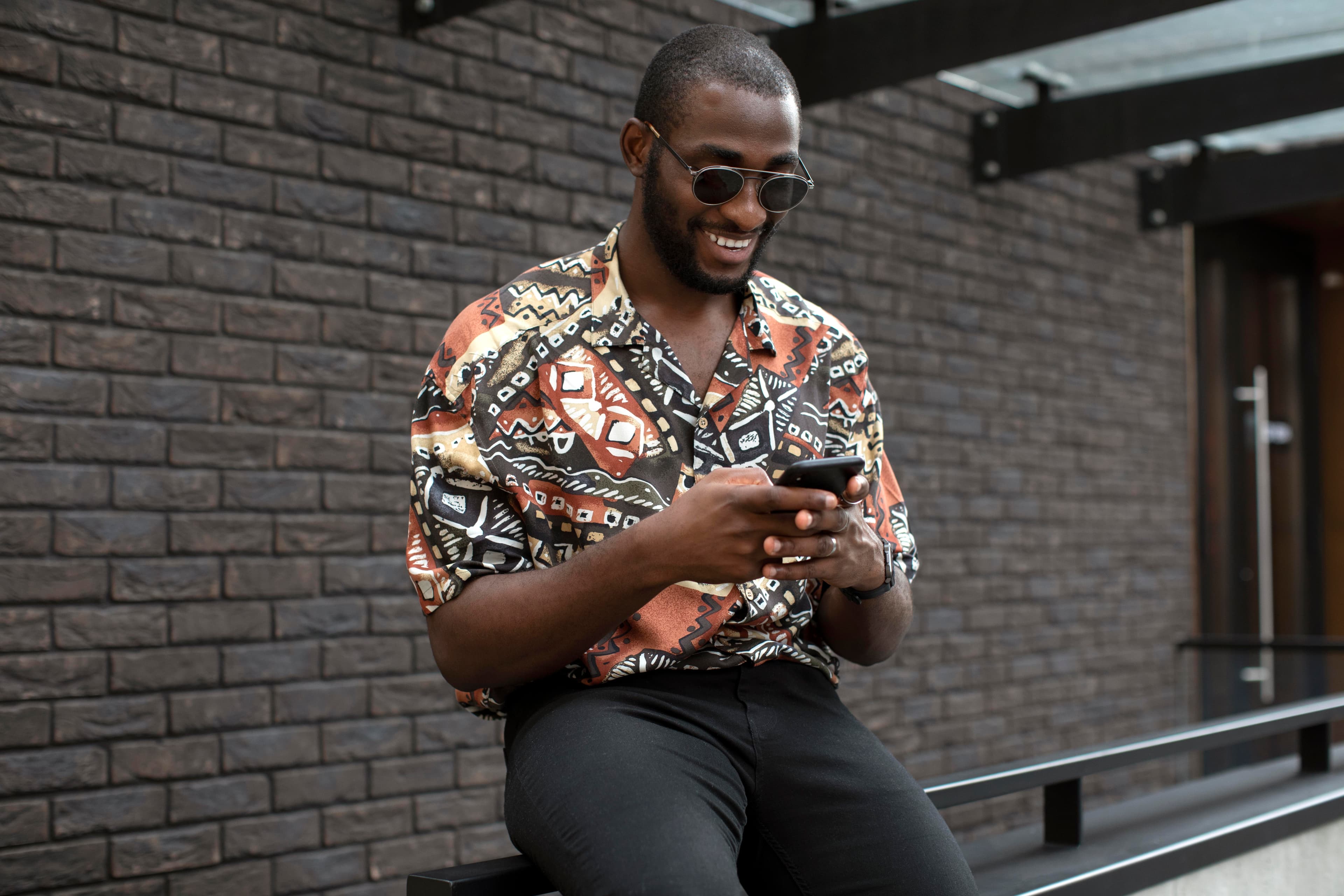 A man in a colorful Hawaiian shirt looking at his phone screen.