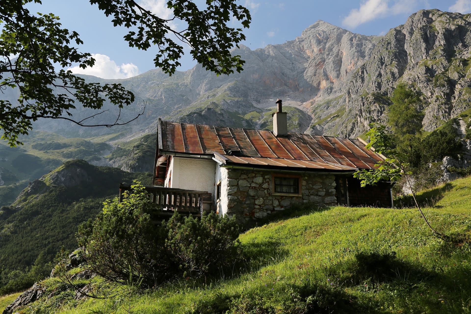 A scenic view of a cabin with a towering mountain range.